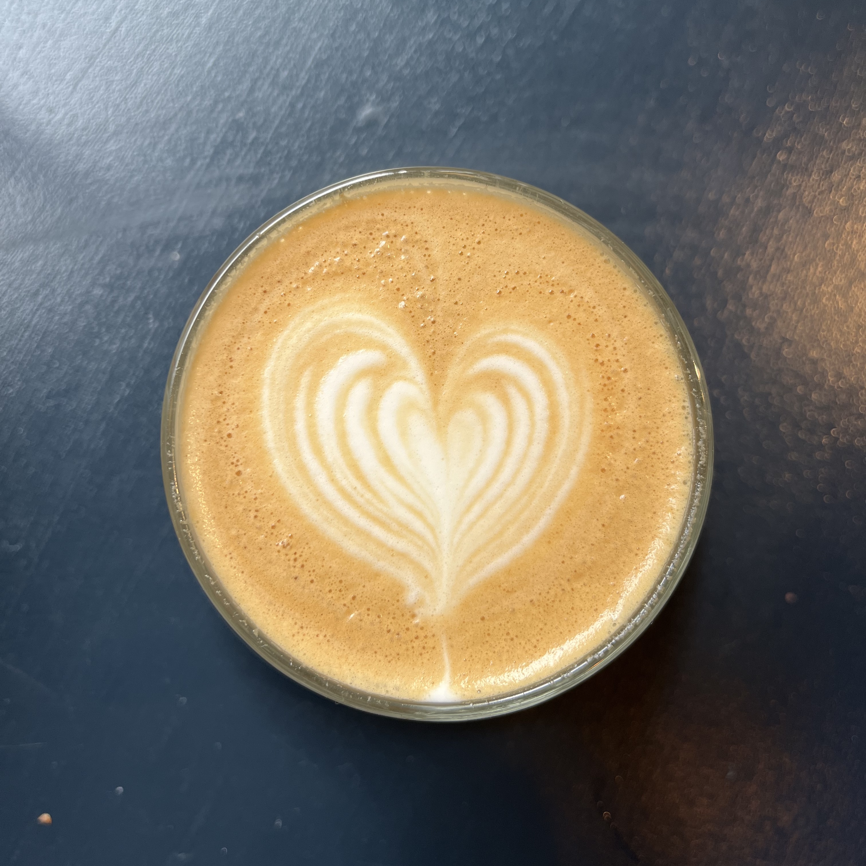 A coffee cup from above with latte art in the shape of a heart