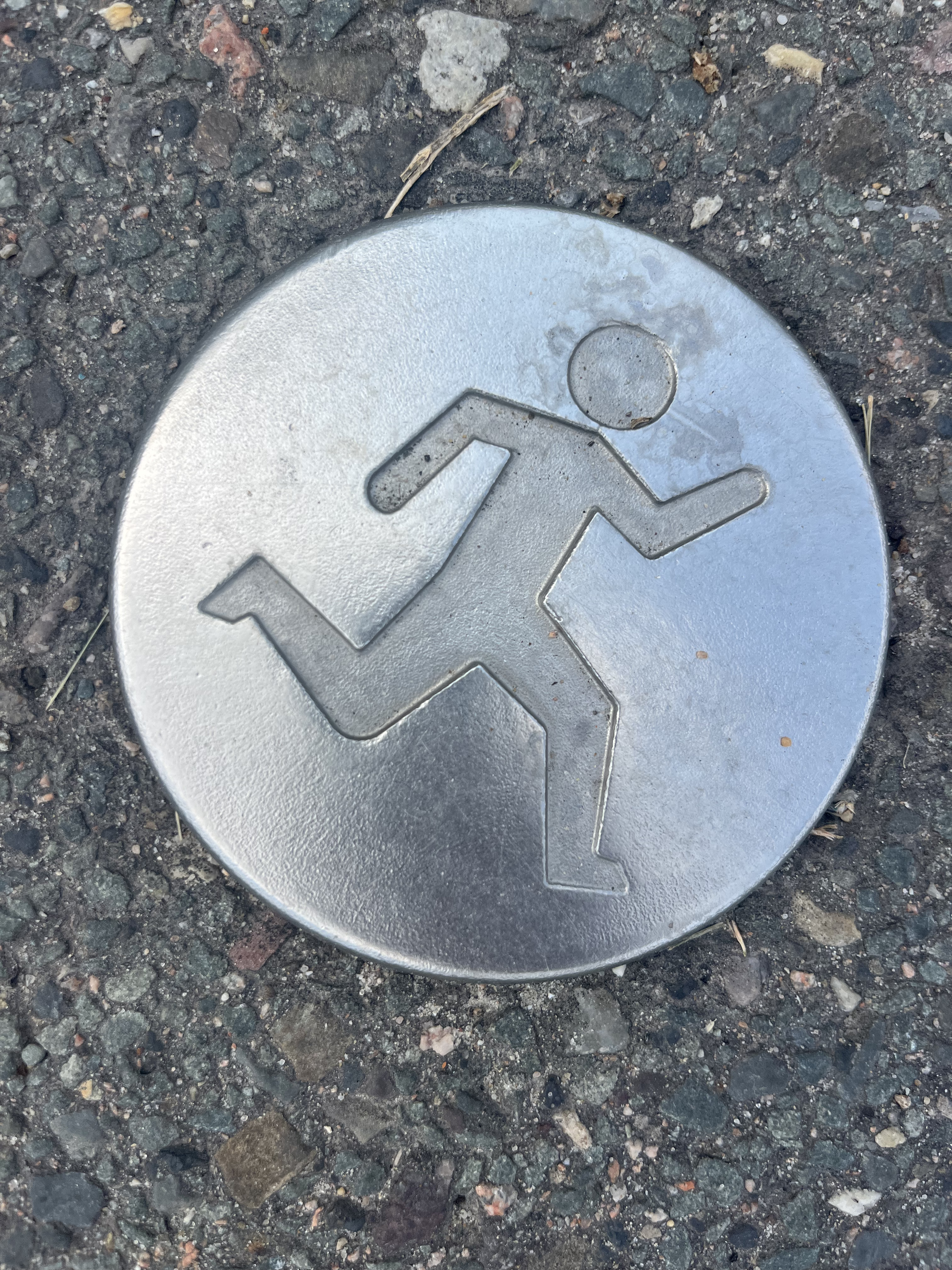 A road sign on pavement with a depiction of a person running